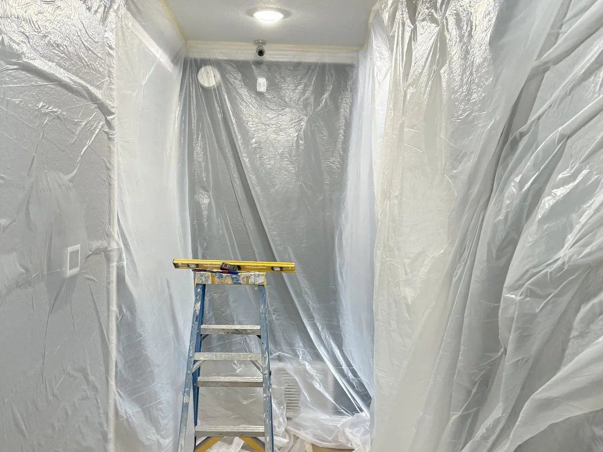 Room sealed off with plastic sheeting and a ladder set up for painting